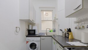 Una cocina compacta con lavadora, microondas, pileta y un ventanal.