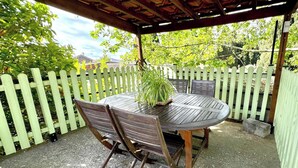 An outdoor patio with a round wooden table and chairs, surrounded by a white picket fence. - Chai du Canal - SALLELES D'AUDE (SALLELES D AUDE)