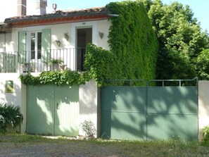 Un edificio con un portón verde, un balcón y una puerta.