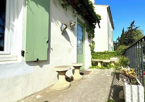 A building with a green door, a window with shutters, and a stone bench.