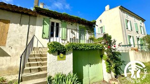 Un bâtiment à deux étages avec une porte verte, un escalier menant à l’entrée et une enseigne indiquant qu’il s’agit d’un gîte de France.