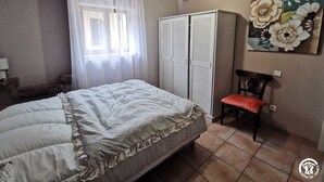 Ein Schlafzimmer mit Bett, Stuhl, Kleiderschrank und einem Bild an der Wand.