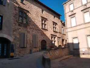 Une rue étroite bordée d’immeubles en pierre, dont l’un présente une entrée visible et l’autre un balcon.