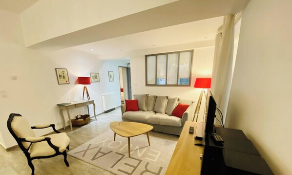 A living room with a sofa, a chair, a coffee table, a TV, and a lamp. - L'Epicerie - CAUNES MINERVOIS (CAUNES MINERVOIS)