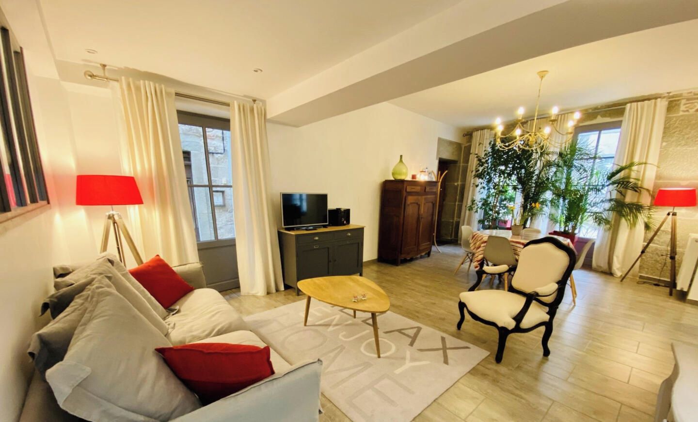 Una sala de estar con sofá, sillón, mesa de centro, televisor y un comedor con mesa y sillas.