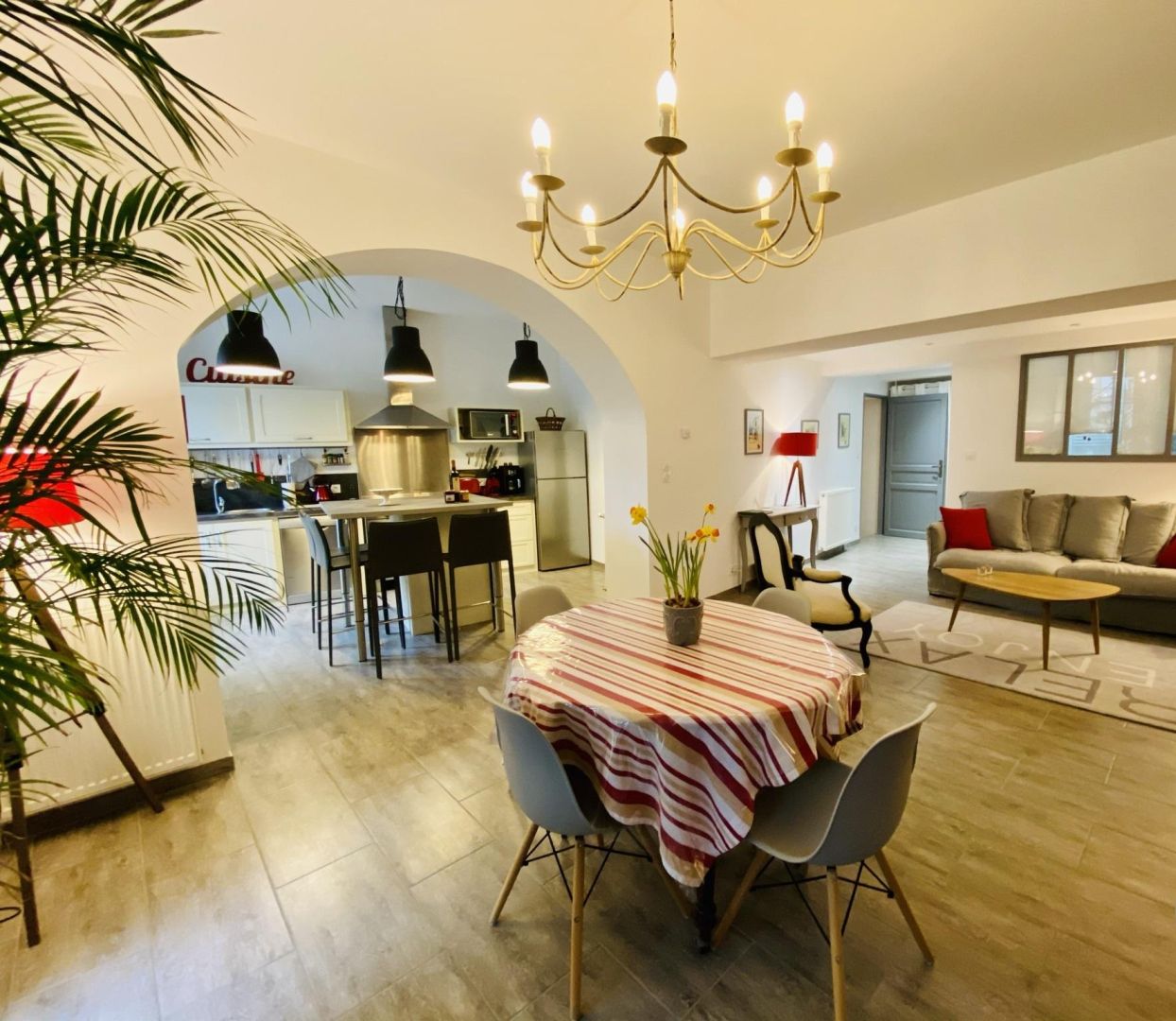 Una sala de estar moderna con comedor, una cocina al fondo y una araña.