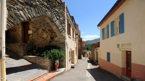 A narrow street with stone buildings, a potted plant, and a clear sky.