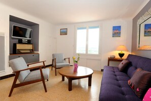 A living room with a sofa, two armchairs, a coffee table, a television, and a radio.