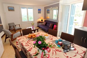 Ein Essbereich mit Tisch für zwei Personen, einer Couch und Blick ins Freie.
