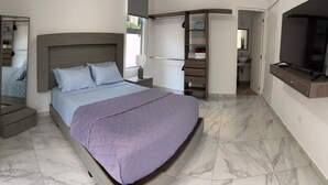 Une chambre moderne avec un grand lit, une télévision et un dressing.