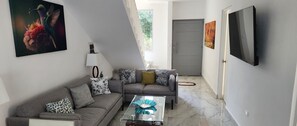 A modern living room with a grey sofa, a glass coffee table, and a mounted TV. - A peaceful Yance Villa, 5 min from the beautiful Puerto Morelos beach (Cancún)