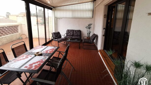Tilava patio, jossa on pöytä ja tuoleja, sohva ja ruukussa oleva kasvi.