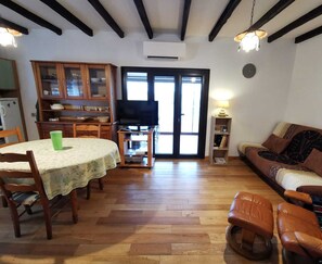Un salon chaleureux avec une table à manger, des chaises en bois, un canapé et un téléviseur.
