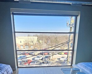 Ein Zimmer mit einem großen Fenster, das auf einen Parkplatz und Gebäude blickt.