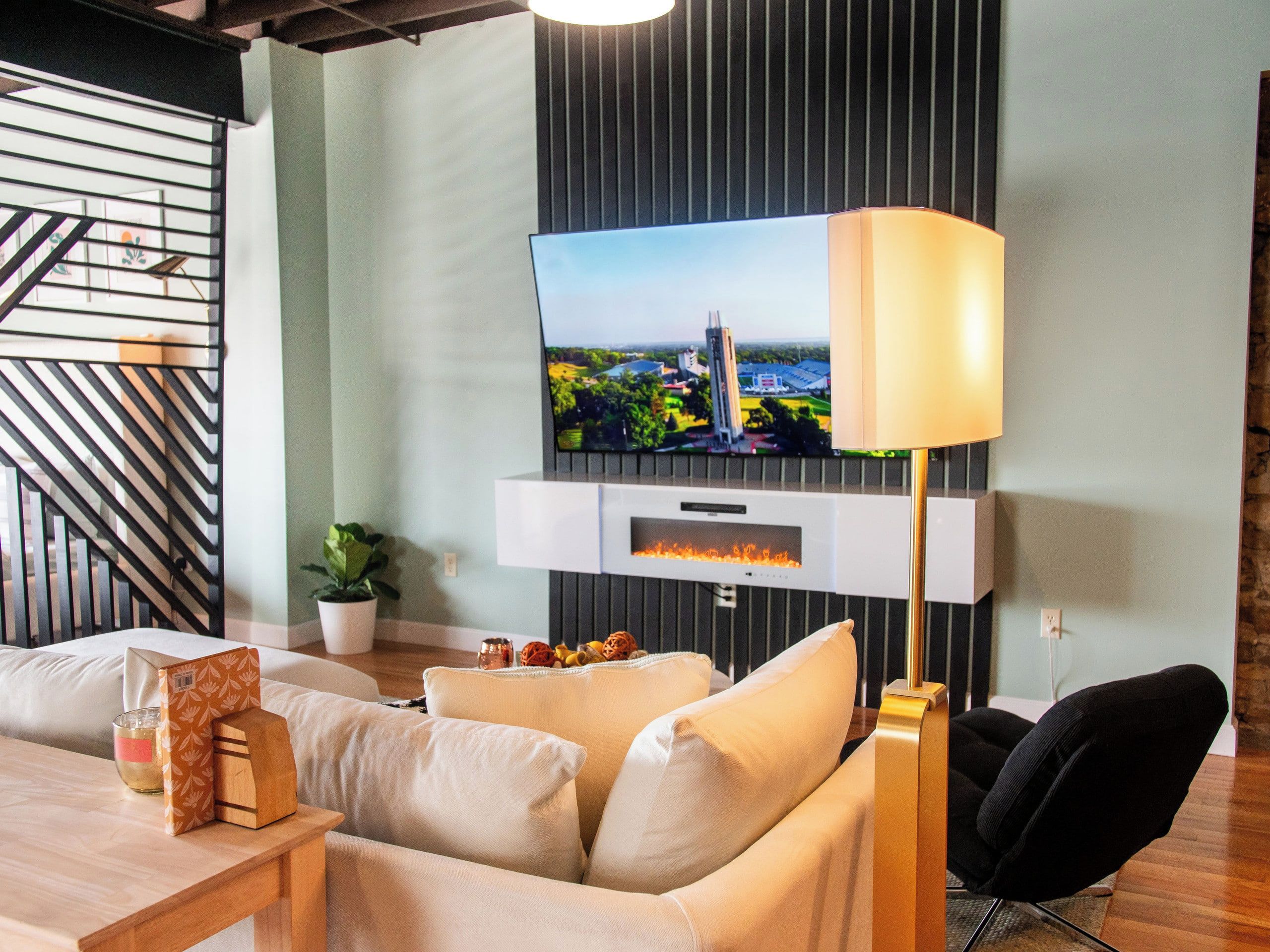 A modern living room with a flat-screen TV mounted on a wall, a sofa, a coffee table, and a floor lamp.