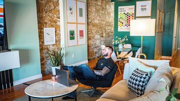 Een modern interieur met een stenen muur, een ronde tafel met een laptop, een bank en een lamp.