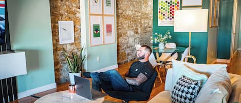 Een modern interieur met een stenen muur, een ronde tafel met een laptop, een bank en een lamp.