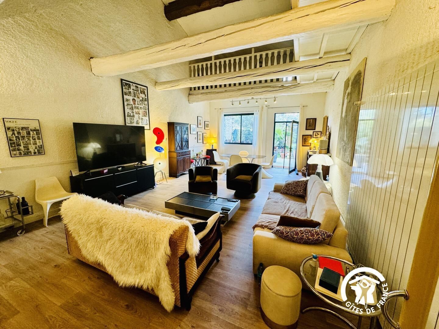 A living room with a TV, sofa, chairs, and a dining area.