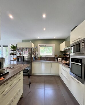 A modern kitchen with white cabinets, stainless steel appliances, and a central island.