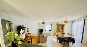 A dining area with a table and chairs, a television, and a cabinet.