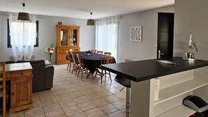 Una cocina moderna con una isla central, comedor con sillas y un armario de madera.