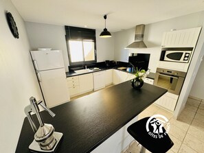 Une cuisine moderne avec un plan de travail noir, des armoires blanches, un four encastré et un four à micro-ondes.