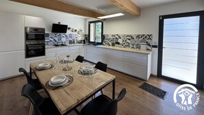 Une cuisine moderne avec une table à manger en bois pour quatre personnes, des meubles blancs et un crédence à motifs noir et blanc.
