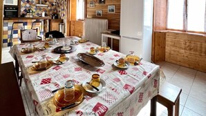 A wooden interior with a dining table set for a meal, a kitchen area, and a refrigerator.