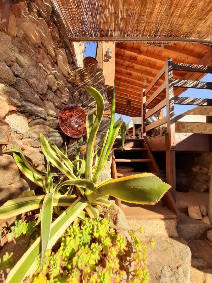 A stone wall with a wooden staircase leading to a wooden deck.