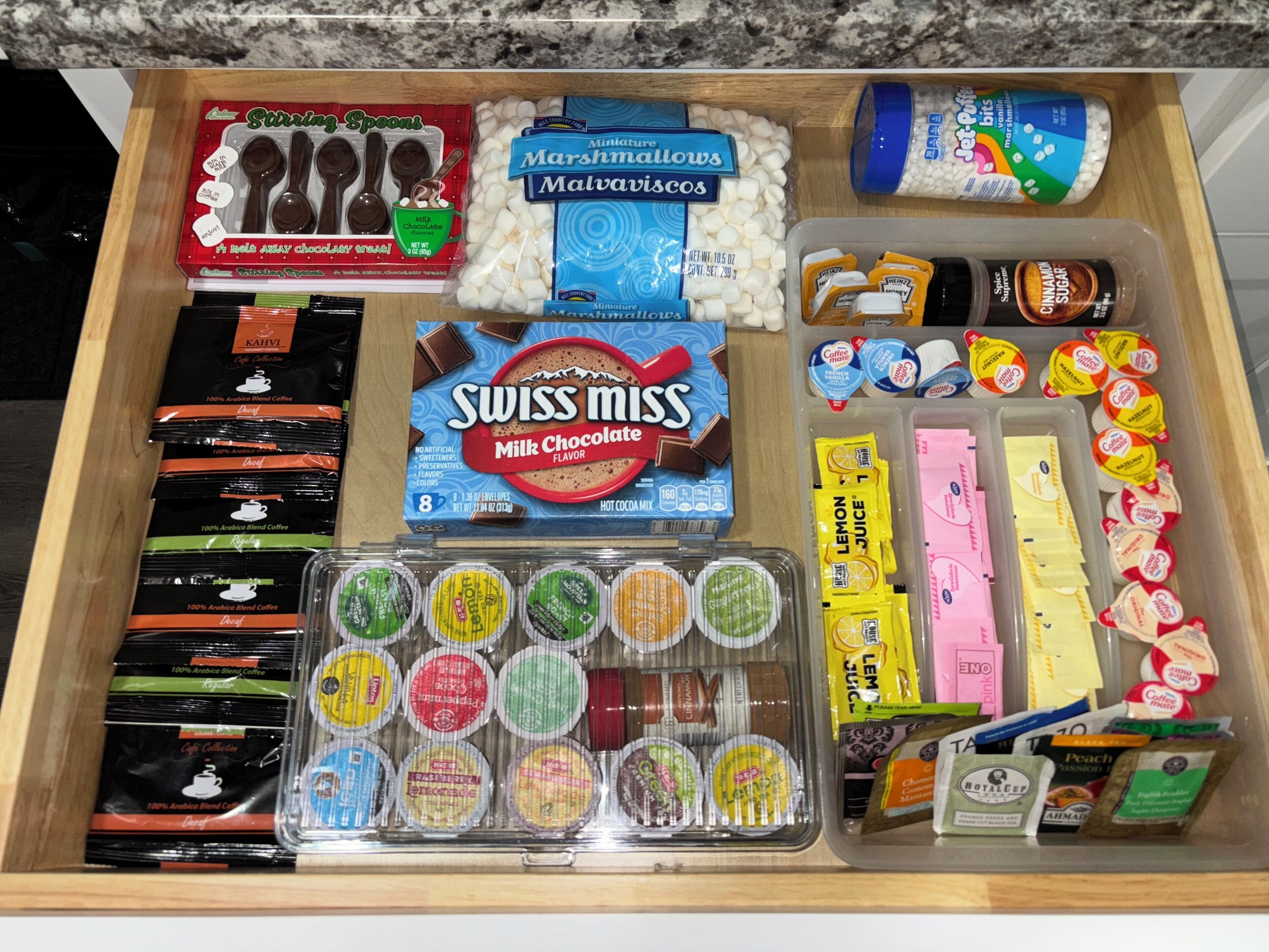 Un tiroir rempli de divers produits alimentaires, notamment des guimauves, du chocolat, du café et des en-cas.