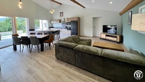 A modern living space with a dining area, kitchen, and a TV in the living room.