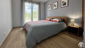 A bedroom with a bed, a nightstand, a lamp, and a window with curtains.