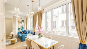Een ruime woonkamer met een eethoek, grote ramen en uitzicht op de stad.