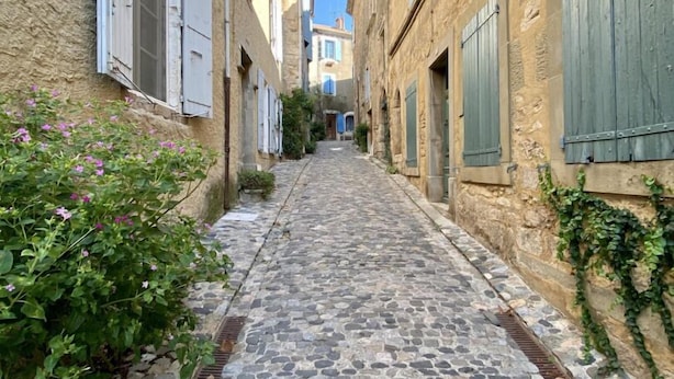 A narrow cobblestone street flanked by stone buildings with shutters, leading to a distant building with a visible balcony. - Saint Genes - CAUNES MINERVOIS (CAUNES MINERVOIS)