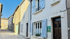 A narrow street with buildings on either side, a manhole cover, and a door with a sign. - Saint Genes - CAUNES MINERVOIS (CAUNES MINERVOIS)