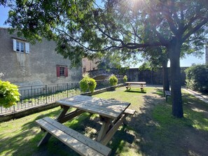 A picnic area with wooden tables and benches, surrounded by greenery and a stone wall. - Saint Genes - CAUNES MINERVOIS (CAUNES MINERVOIS)