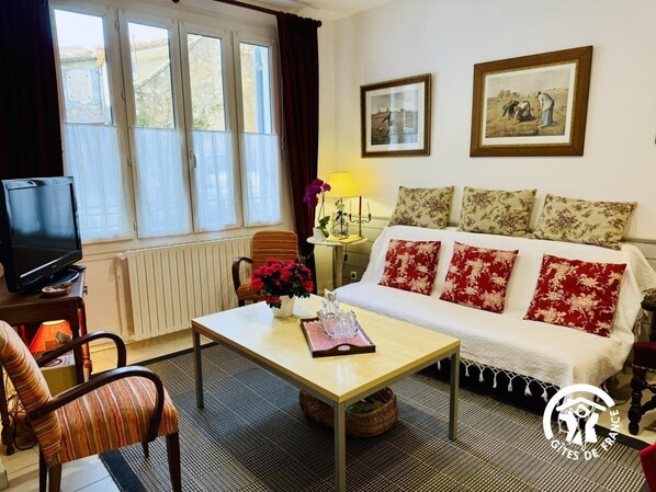 A cozy living room with a sofa, a coffee table, a TV, and a window with curtains. - Saint Genes - CAUNES MINERVOIS (CAUNES MINERVOIS)