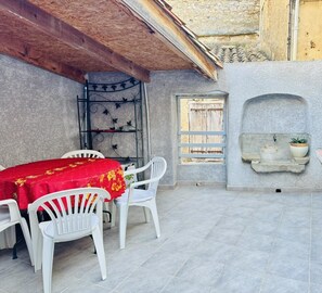 A patio area with a table and chairs, a stone wall with a built-in sink, and a wooden ceiling. - Saint Genes - CAUNES MINERVOIS (CAUNES MINERVOIS)