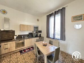 A compact kitchen with wooden cabinets, a built-in microwave, and a dining area with a table and chairs.