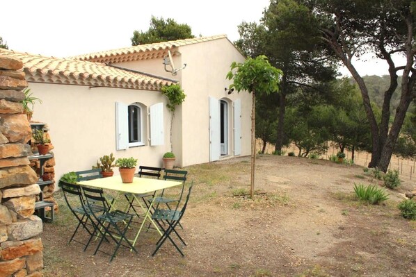 Una casa rustica con tetto in tegole, un muro in pietra e un tavolo con sedie nel cortile.