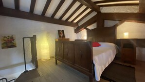A bedroom with a wooden bed, a nightstand, a wall-mounted lamp, and a painting. - Le yucca - ALENYA - Gîte (ALENYA)