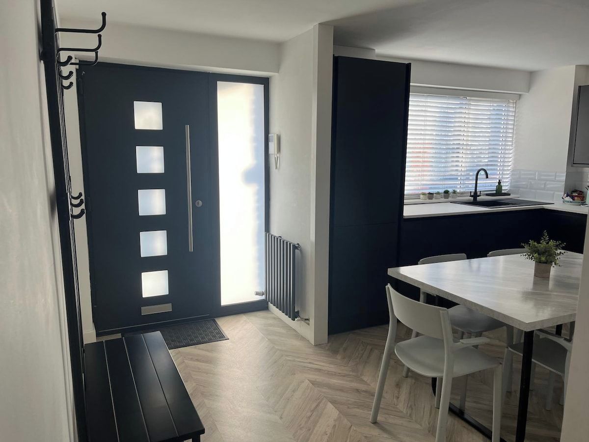 Una cucina moderna con zona pranzo, una panca e una finestra con persiane.