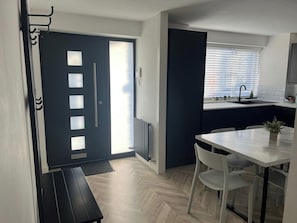 Una cucina moderna con zona pranzo, una panca e una finestra con persiane.
