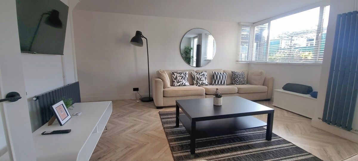 A modern living room with a sofa, a coffee table, a floor lamp, and a large mirror.