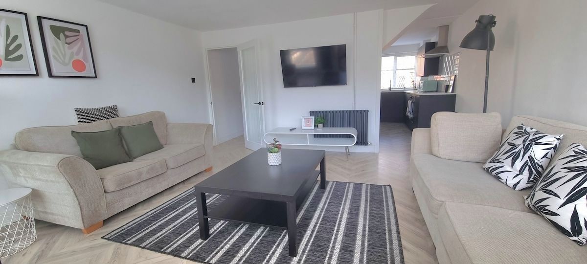 Ein modernes Wohnzimmer mit einer Couch, einem Couchtisch und einem an der Wand befestigten Fernseher.