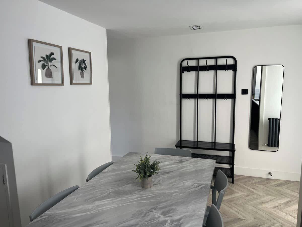 A modern conference room with a marble table, chairs, a black metal rack, and a mirror on the wall.