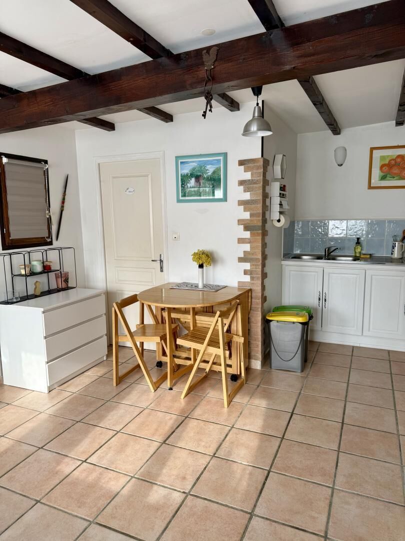 A kitchen with white cabinets, a wooden table, and a tiled floor.