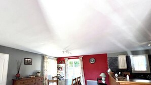 A spacious kitchen with a dining area, featuring a wooden table and chairs, a kitchen island, and a red accent wall. - Le Ligno - QUILLAN - Gîte (QUILLAN)
