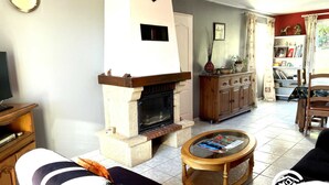 A living room with a fireplace, a television, a sofa, a coffee table, and a bookshelf. - Le Ligno - QUILLAN - Gîte (QUILLAN)
