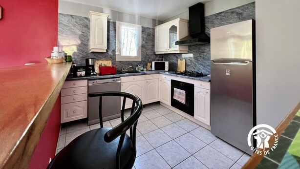 A modern kitchen with white cabinets, a black stove, and a stainless steel refrigerator. - Le Ligno - QUILLAN - Gîte (QUILLAN)